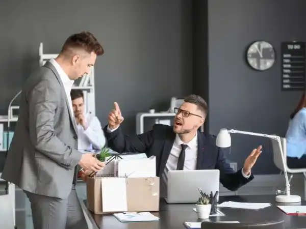 un lavoratore dipendente sta alzando un dito e sembra litigare con il suo datore di lavoro, gesto di insubordinazione del lavoratore.
