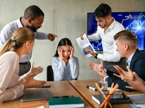 rappresentazione di mobbing sul lavoro con un dipendente accerchiata e criticata dai colleghi durante una riunione