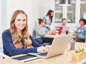 Una giovane apprendista sorride mentre lavora al computer in un ambiente d'ufficio