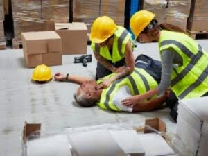 Due colleghi soccorrono un uomo a terra privo di coscienza, vittima di un infortunio sul lavoro